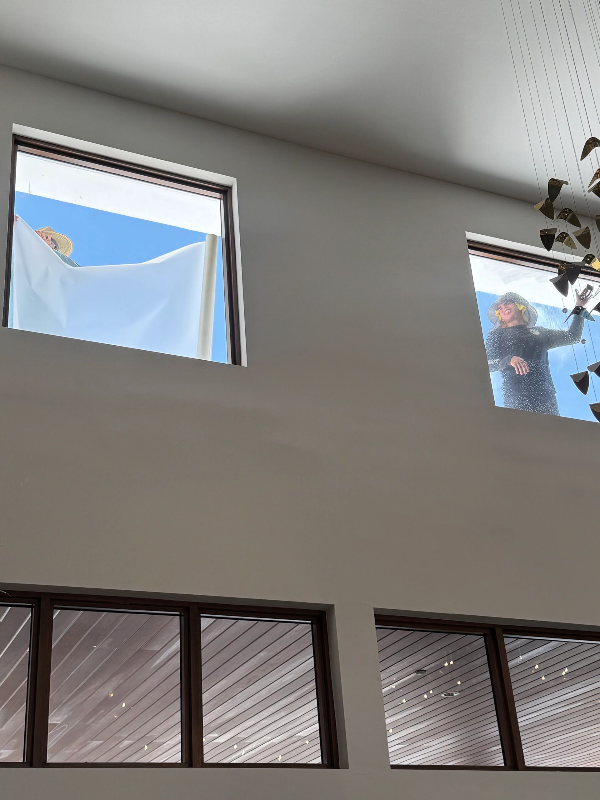 Two people cleaning exterior windows of a modern house.