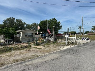 Small house with fenced yard and American flag on a clear day.
