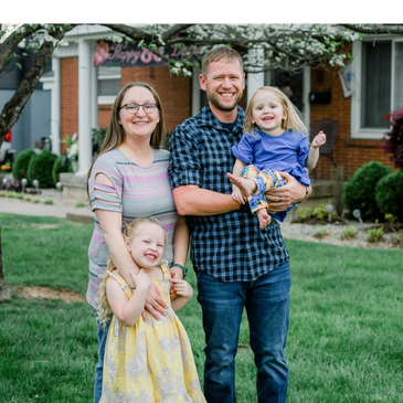 Happy family smiling outdoors in front of a house.