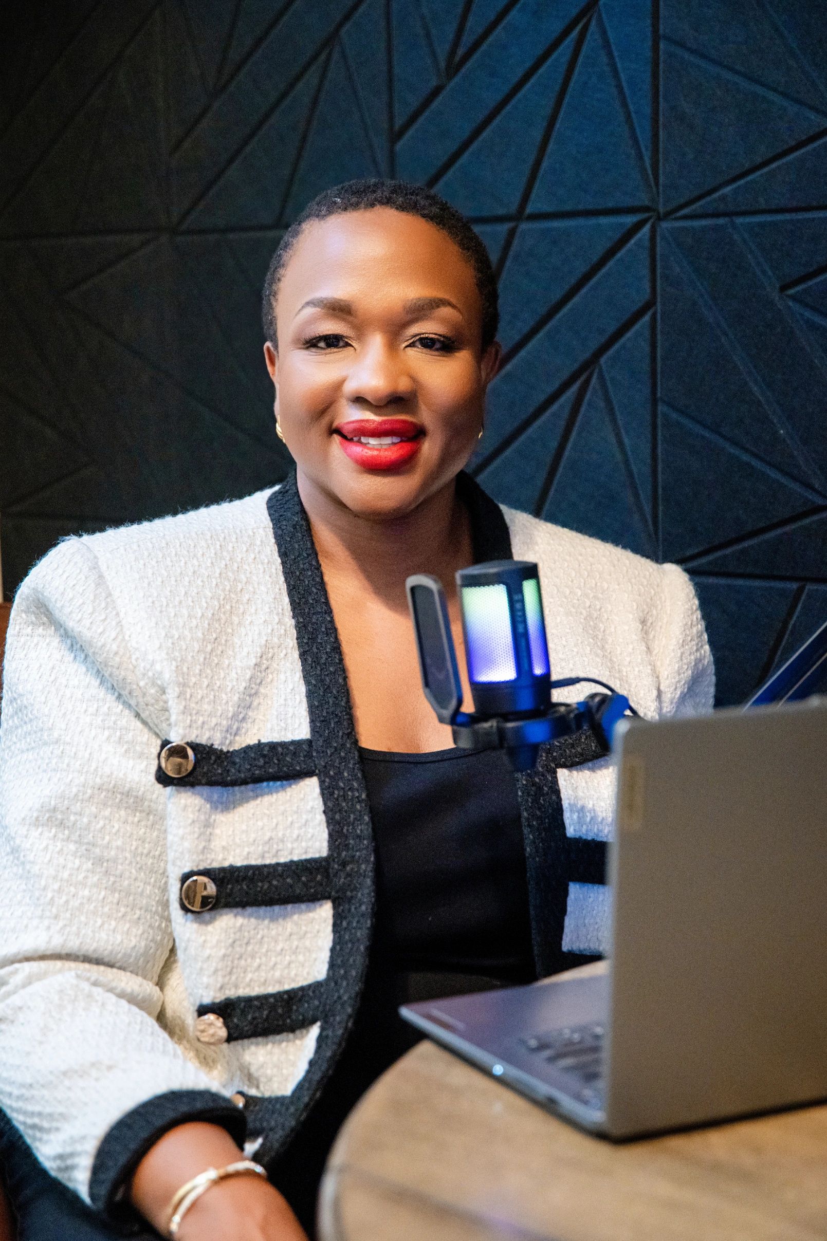 Photo of Lola in a black and white dress, seated in a chair, holding a coffee mug.
