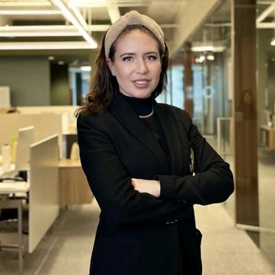 Confident professional woman in a black blazer standing in a modern office.