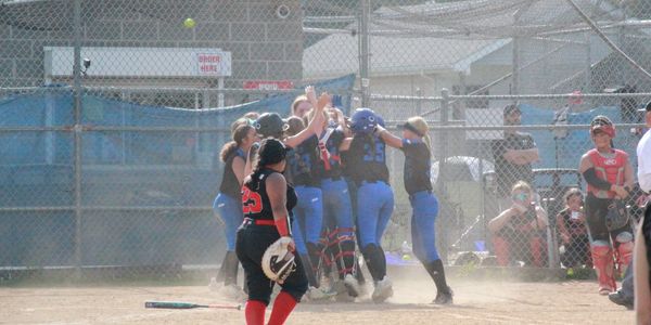 Youth softball team celebrating on the field after a win.