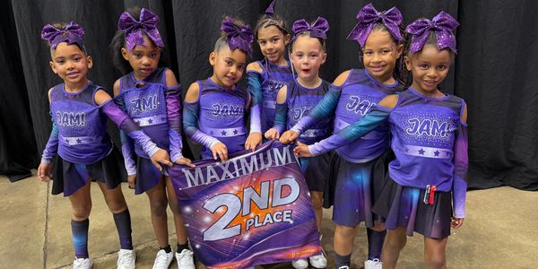 Seven young cheerleaders in purple uniforms hold a 2nd place banner.