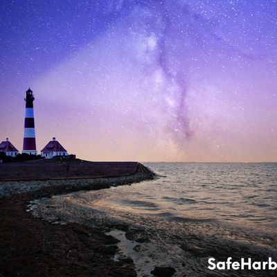 Lighthouse at dusk under a rainbow sky, symbolizing Safe Harbor's support in therapy and counseling.
