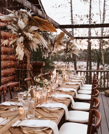 A bohemian-style micro wedding tablescape with a harvest table, harvest chairs, and pampas grass flo