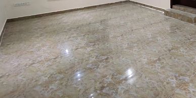 Empty room with marble floor, arched window, and wooden door.