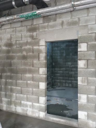 Concrete block wall with a doorway and exposed pipes labeled for chilled water.