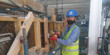 Construction worker wearing safety gear using a power tool on a wooden structure.