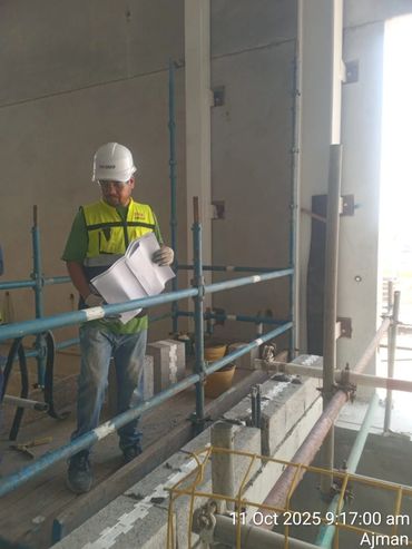 Construction worker reviewing plans on site with safety gear.
