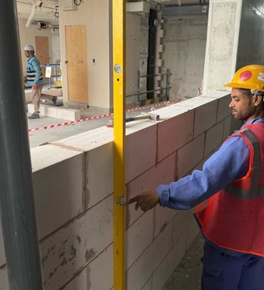 Construction worker checking wall alignment with a level tool.