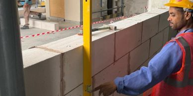 Construction worker checking wall alignment with a level tool.