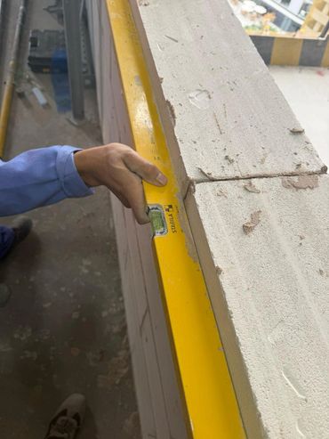 Worker using a yellow spirit level to check wall alignment.