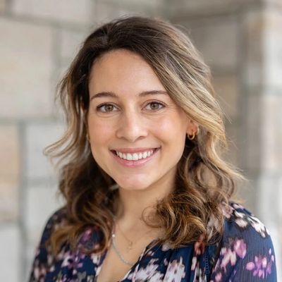 Smiling woman with wavy hair and floral blouse.