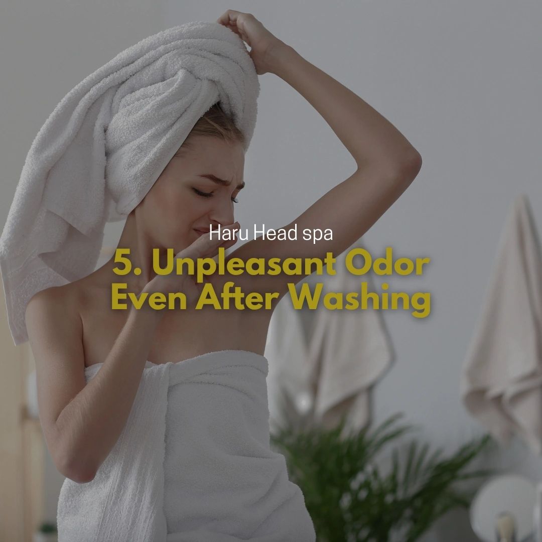 A young woman with a towel on her head and wrapped in a bath towel is looking concerned while raising her arm, indicating a potential issue with body odor. The text overlay states '5. Unpleasant Odor Even After Washing' and 'Haru Head spa'.