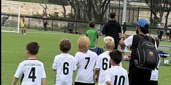 Young soccer players and coach walking on the field after a game.