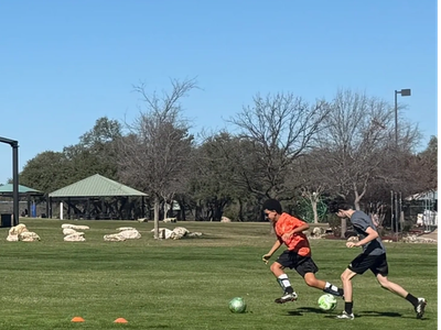 Two boys playing soccer on a grassy field.
