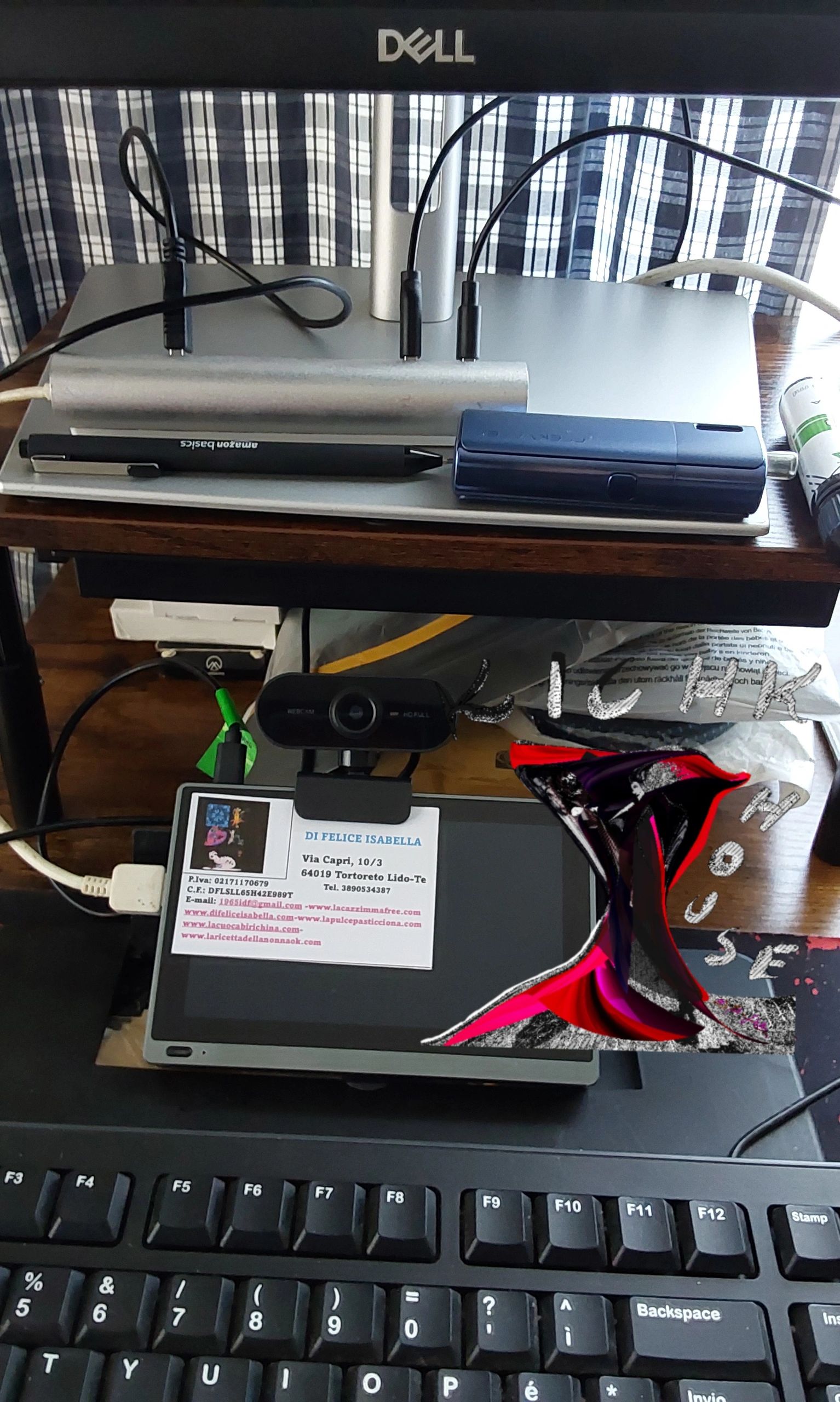 Scrivania con laptop, webcam e biglietto da visita.