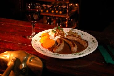 Plate with sausages, sauerkraut, and potato dumplings on a wooden table.