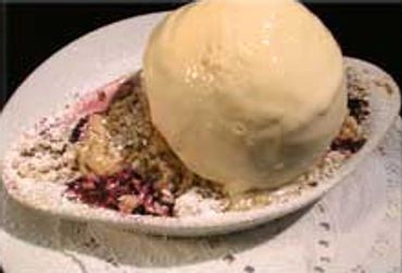 A scoop of vanilla ice cream on a berry crumble dessert.