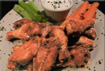 Plate of buffalo chicken wings with celery, carrot sticks, and ranch dip.