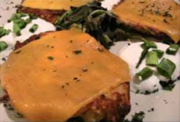 Two cheeseburgers with melted cheddar on a white plate.