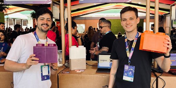 Dois homens segurando blocos coloridos em evento.
