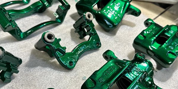 Shiny green painted metal automotive parts arranged on a table.