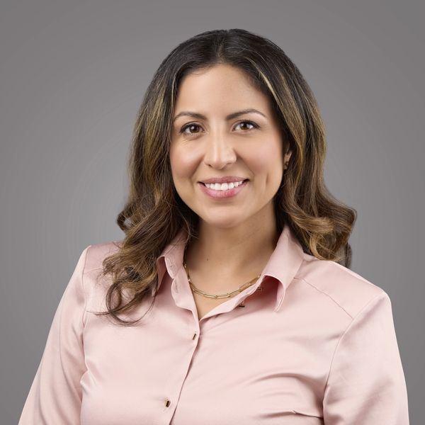 Smiling woman with wavy hair in a pink blouse.