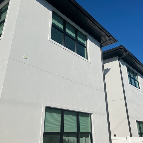Modern white two-story building with large windows under a clear blue sky.