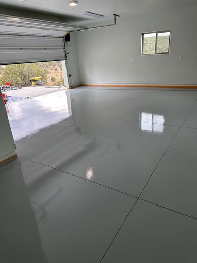 Shiny, freshly coated garage floor with open door and window.