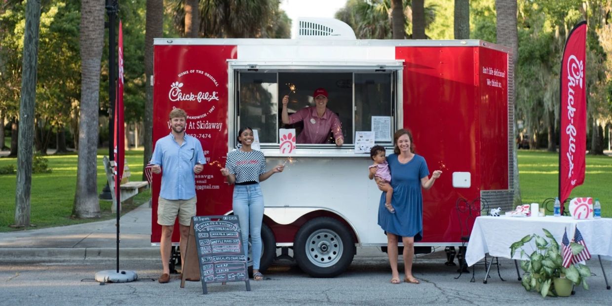 People celebrate with sparklers at a Chick-fil-A food truck outdoors.