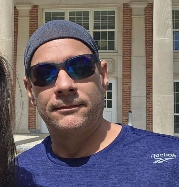 Man wearing sunglasses and a headband outside a building.