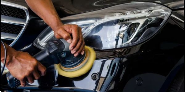 Person polishing a black car with an electric buffer.