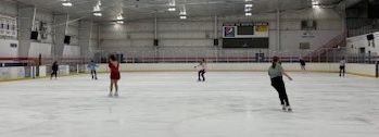 People skating on an indoor ice rink.