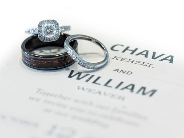 Three wedding rings placed on a wedding invitation for Chava Kerzel and William Weaver.