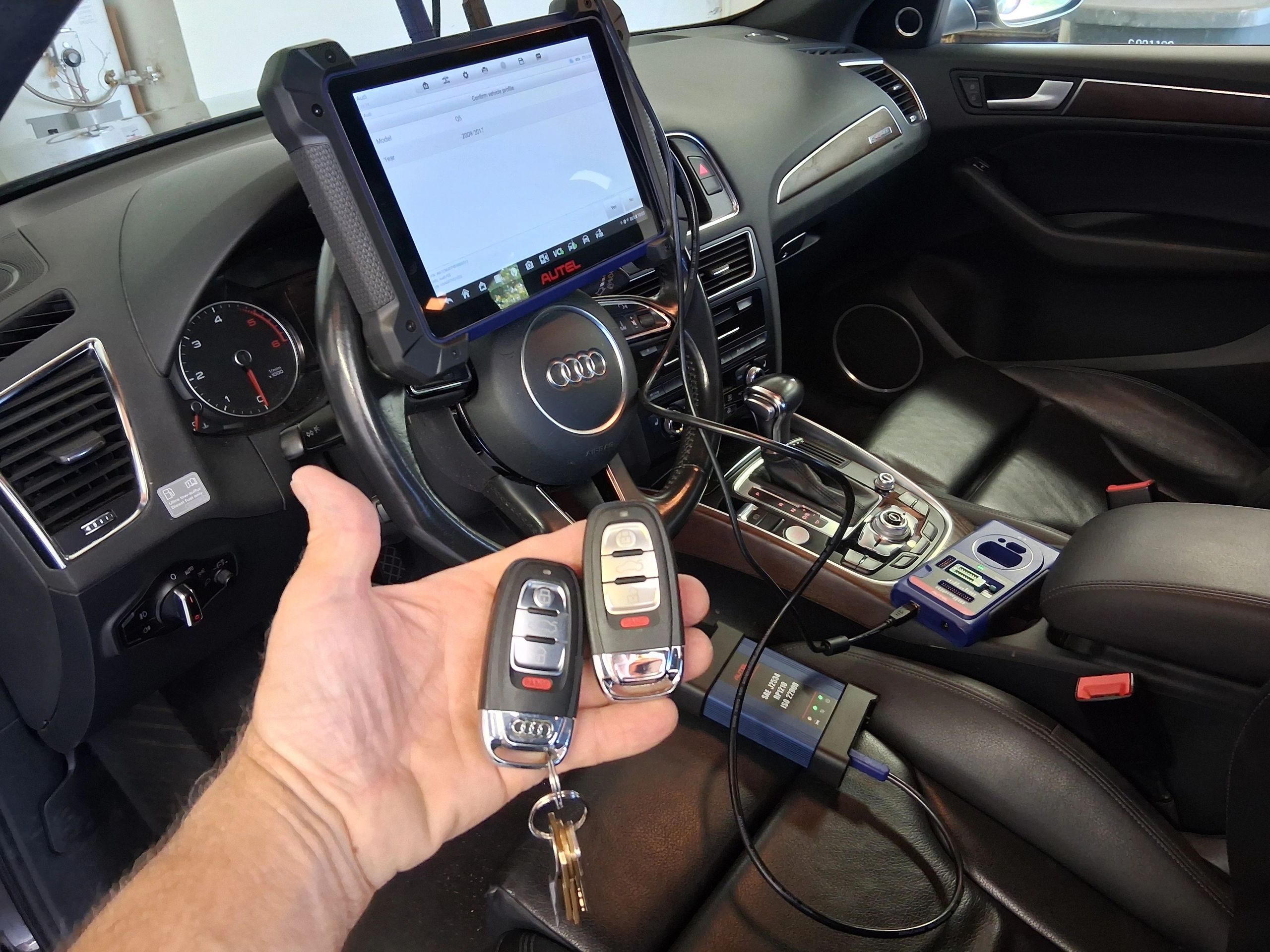 A new programmed and cut spare aftermarket Audi smart key next to OEM key for a 2015 Audi Q5