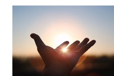 Hand with sky and sun setting in the background