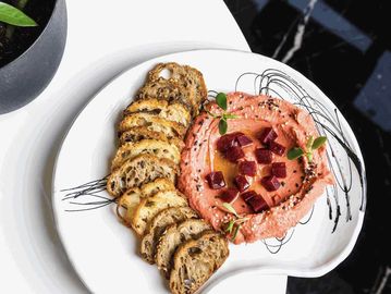 Twisted Chili Hummus dip, topped with olive oil and sesame seeds, homemade Sourdough chips