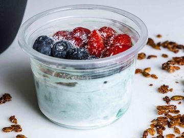 Spirulina Greek yogurt mix, topped with strawberries, blueberries, granola, coconut and honey drizzles  