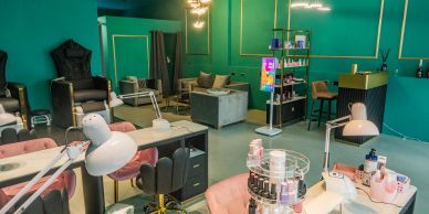 Modern nail salon with teal walls and cozy seating.