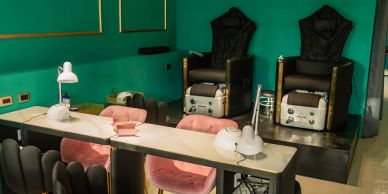 Modernes Nagelstudio mit grünen Wänden und rosa Stühlen.