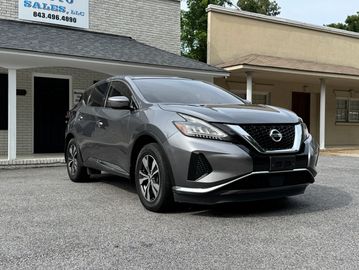 Gray Nissan SUV parked in front of a sales building.