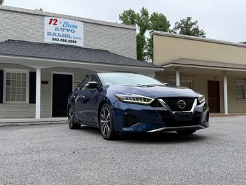 Blue Nissan sedan parked in front of 12 Eleven Auto Sales.