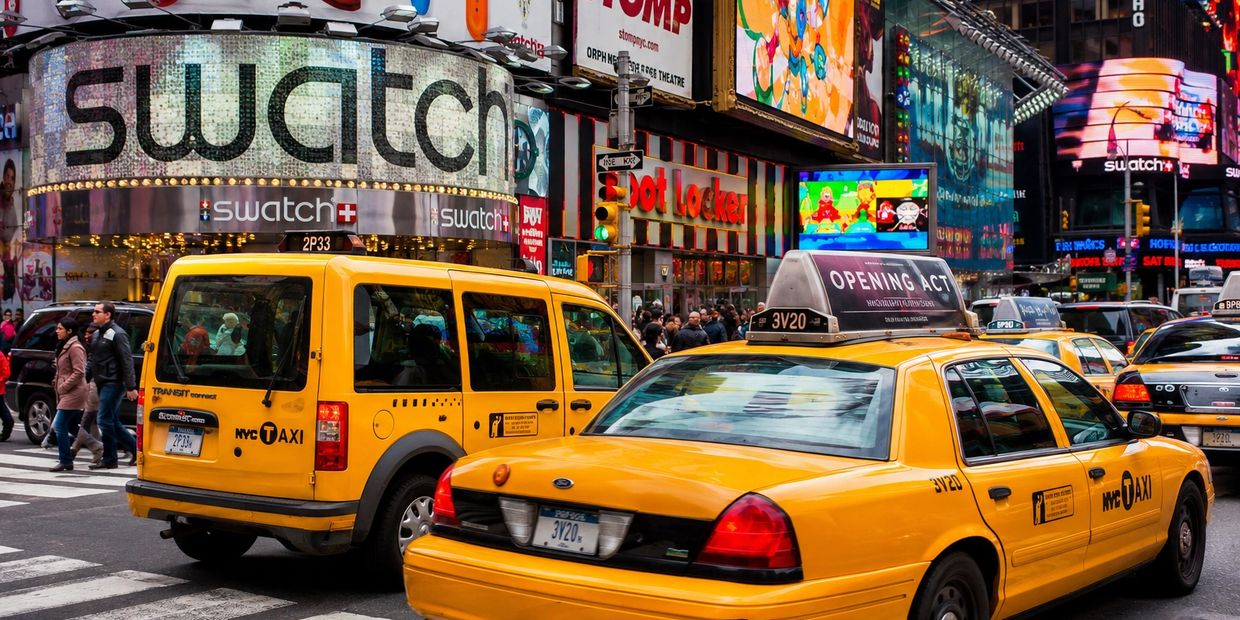 Busy New York street with yellow taxis and vibrant advertisements.
