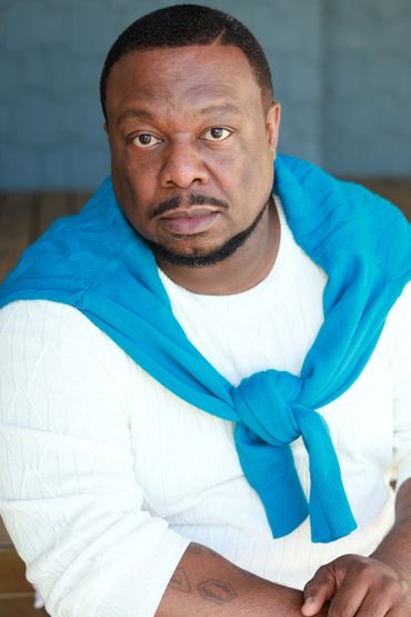 Man wearing white sweater with blue sweater draped over shoulders.