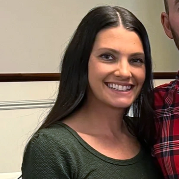 Family of five posing happily in front of a decorated Christmas tree indoors.
