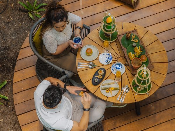 Two people enjoying a meal at a round wooden table outdoors.