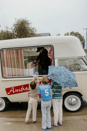 Three children buy treats at a vintage ice cream truck.