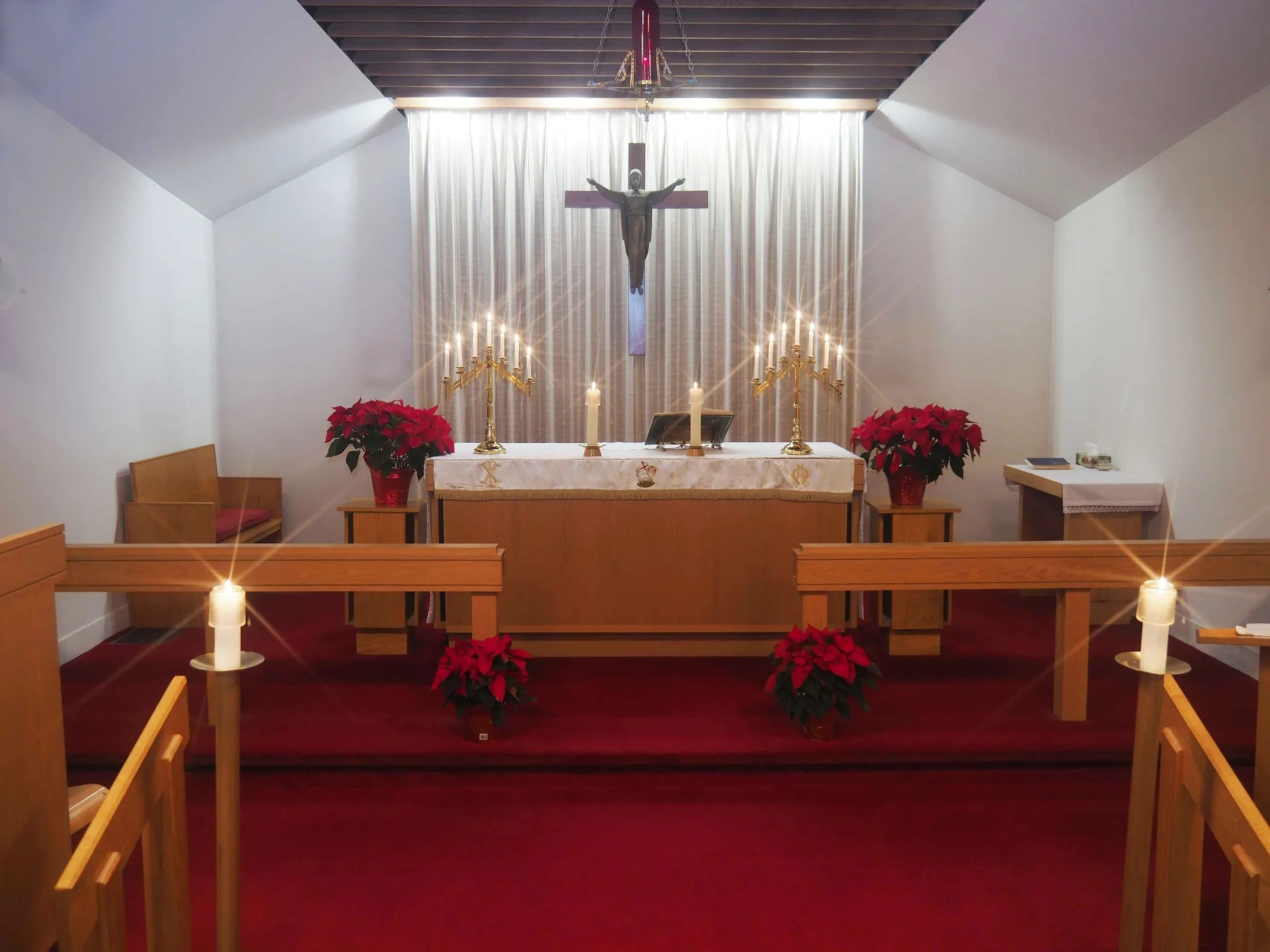 A serene church altar with candles, poinsettias, and a crucifix.