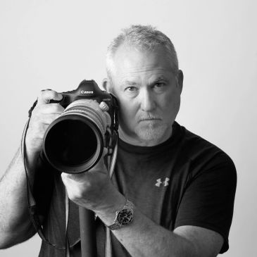 Man holding a camera with a serious expression.